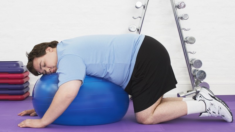 Obézny muž leží na fitlopte_ilustračné foto